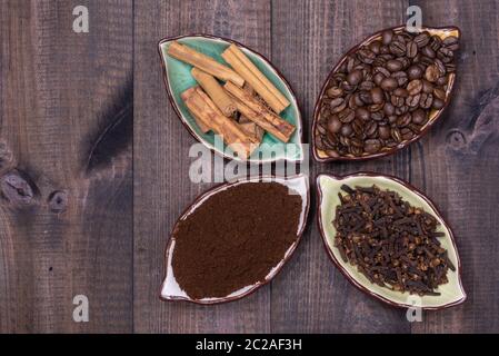 Four cups with coffee beans, cinnamon, cloves and coffee powder Stock Photo