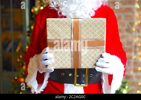 Santa Claus secretly putting gift boxes under the Christmas tree Stock Photo