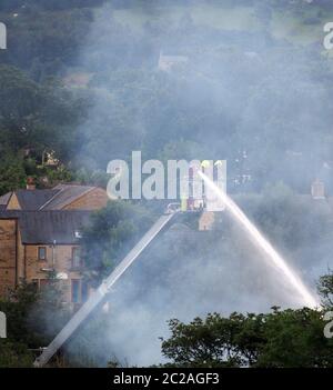 firemen on an elevated platform putting out the fire at the former walkeys clogs mill in hebden bridge Stock Photo