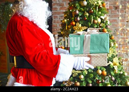 Santa Claus secretly putting gift boxes by the Christmas tree Stock Photo