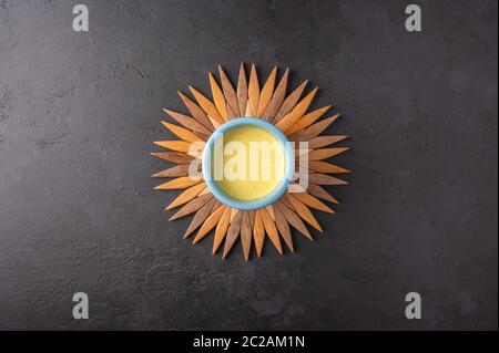 Ceramic blue cup with traditional Indian masala chai tea on a bamboo stand in the form of the sun on a dark background. Top view with copy space Stock Photo
