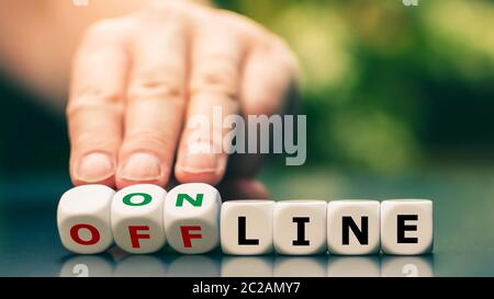 Hand turns dice and changes the expression "offline" to "online". Stock Photo