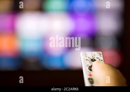 Remote control in hand in from of smart tv Stock Photo
