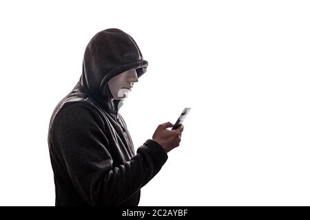 Hooded hacker with mask holding smartphone isolated on white background Stock Photo