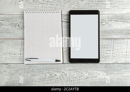 black electronic tablet and paper notebook on vintage shabby white wooden background. the view from the top. flat lay Stock Photo