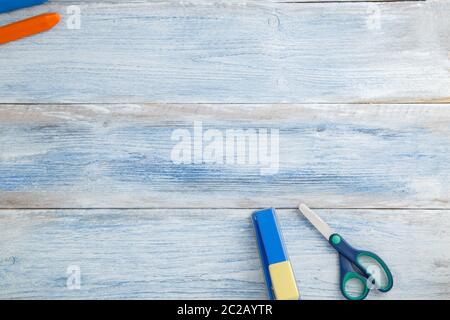 school children's concept. colored pencils or crayons,scissors,stapler on blue and white scuffed vintage wooden background. the Stock Photo