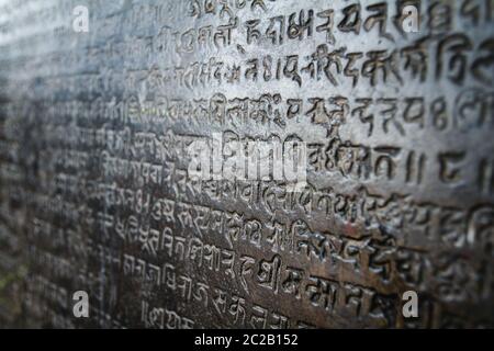 Religious asian nepali writings deeply carved in a dark stone wall in a shrine. Kathmandu, Nepal, Asia Stock Photo