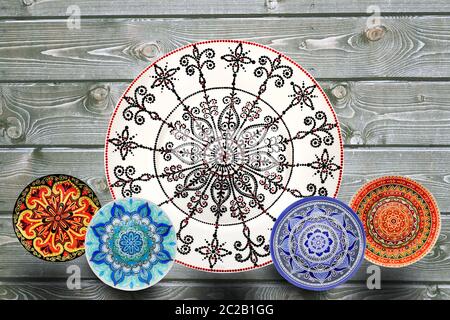 Set of decorative ceramic plates hand painted dot pattern with acrylic paints on a gray wooden background. Copy space. Stock Photo