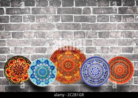 Set of decorative ceramic plates hand painted dot pattern with acrylic paints on a gray wooden background. Copy space. Stock Photo