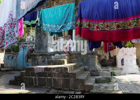 A man sits relaxing on the platform at the entrance of a Shiva temple by Banganga Tank, Walkeshwar, Mumbai, India Stock Photo