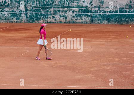 Tennis player. Athlete woman in white skirt and pink t-shirt playing tennis on the court. Sport concept. Stock Photo
