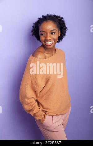 cheerful young black woman with hands in her pockets Stock Photo