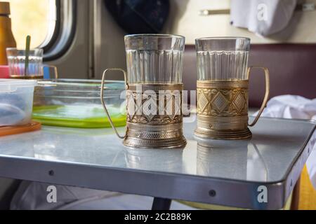 Empty glasses in metal cup holders stand on a table in a train compartment Stock Photo