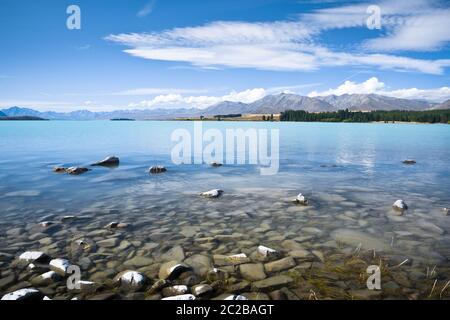 The glacial blue waters of Lake Tekapo, New Zealand, on a sunny summer day. Stock Photo