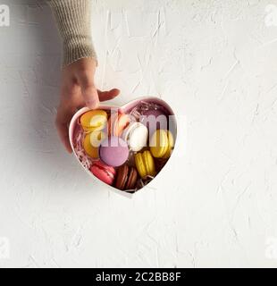 open cardboard box with a baked dessert multi-colored round macarons, top view, white background Stock Photo