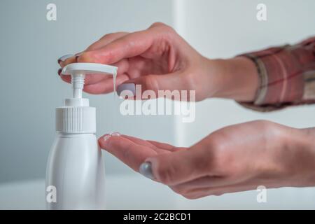 Disinfection, protection, prevention, COVID-19, coronavirus, safety, sanitation concept. Woman pushing dispenser, squeezing out antiseptic gel on palm Stock Photo