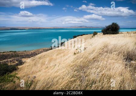 Scenic view across the glacial blue waters of Lake Pukaki, New Zealand on a sunny but windy day. Stock Photo