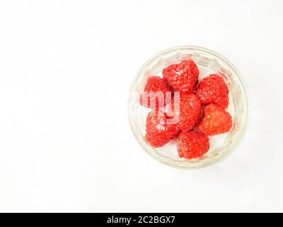 A glass ramekin dish of fresh raspeberries isolated on a white background with copy space to the left Stock Photo