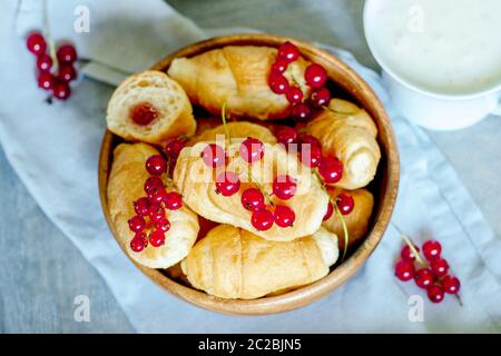 Croissants with currant berries on a wooden tray. The concept of a ...