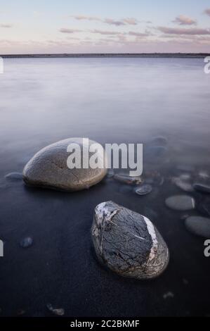 Long exposure of stones in the water at Okarito on the west coast of New Zealand's south island. Stock Photo