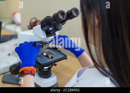 Scientist conducting research taking notes whilst looking through microscope selective focus laboratory assistant is looking through a microscope. Clo Stock Photo