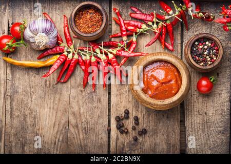 Chili peppers and chili sauce.Hot sauce from chilli peppers and tomatoes on wood background Stock Photo