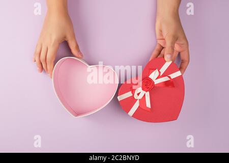 two female hands holding an open desert red heart-shaped box, festive backdrop Stock Photo