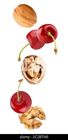 Isolated flying fruit. Falling cherry fruits and walnuts isolated on white background with clipping path as package design element and advertising. fu Stock Photo