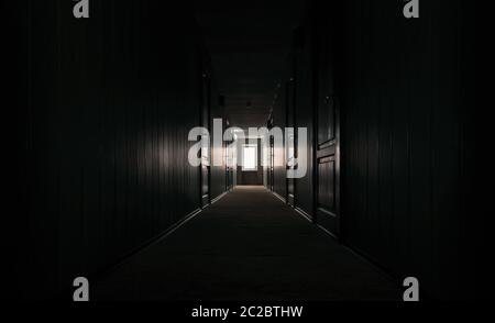 gloomy dark corridor with closed doors of an empty hotel without people during quarantine Stock Photo