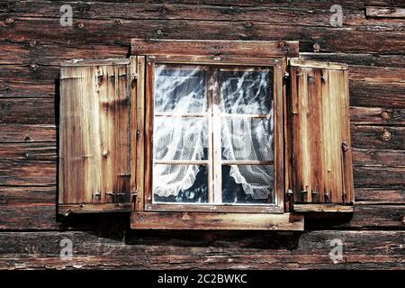 Windows with curtains and shutters on an old wooden house Stock Photo