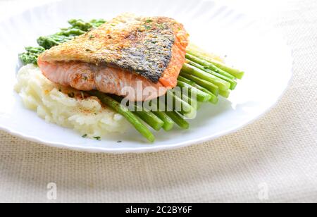 Grilled salmon garnished with asparagus and herbs and mashed potatoes, served on white plated. Stock Photo