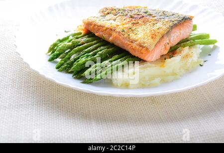 Grilled salmon garnished with asparagus and herbs and mashed potatoes, served on white plated. Stock Photo