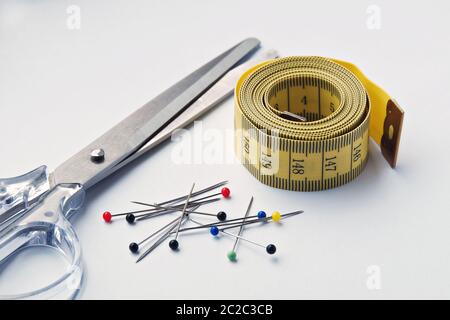 Set for needlework with cissors, measure tape and colored pins isolated on white. Stock Photo