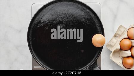 Animation of an egg frying itself in a hot pan jumping from a carton to the edge as butters melts then breaking itself open and frying before being tu Stock Photo