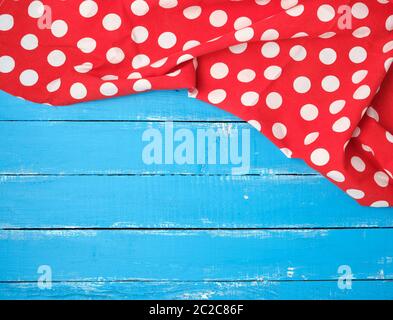 red textile towel with white circles on a blue wooden background, kitchen picnic background, copy space Stock Photo