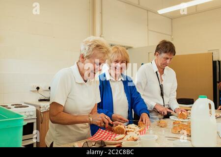 Three senior women having fun making scones, with one smiling at the camera. Stock Photo