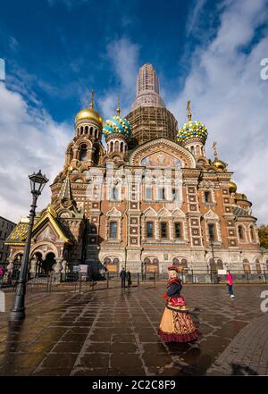 Tourists at Church of the Savior on Spilled Blood facade with woman dressed in period costume, St Petersburg, Russia Stock Photo