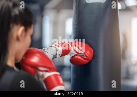 Female boxer in gloves hitting big punching ball during self defence class at gym, empty space Stock Photo