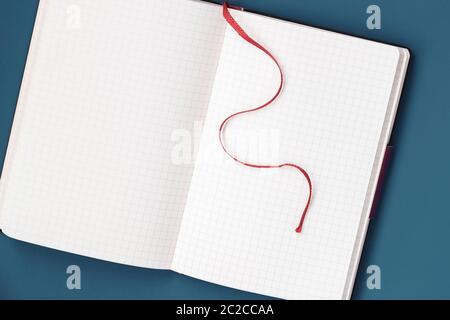 Open notepad in a cage and with red bookmark, on a blue background, copy space Stock Photo