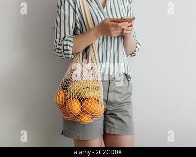 woman with mesh bag on shoulder using smartphone Stock Photo
