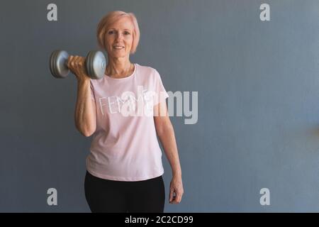 Senior woman lifting weights staying fit at home Stock Photo
