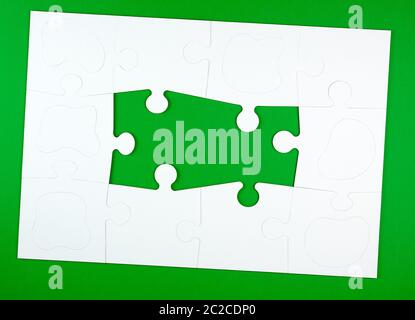 blank white big puzzles on green background, copy space Stock Photo
