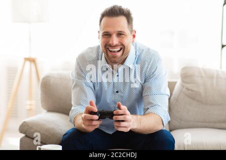 Young man sitting on couch playing video games Stock Photo
