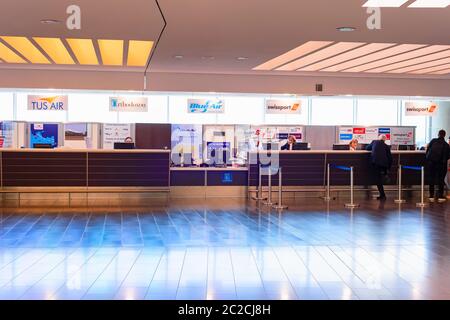 LARNACA, CYPRUS - FEBRUARY 21, 2019: People registering at different airlines check-in desks at international airport terminal Stock Photo