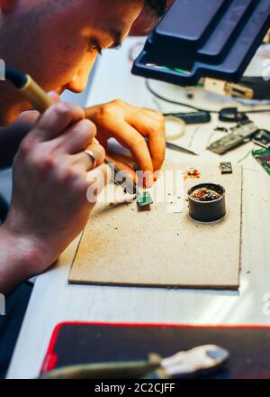 Image of engineer with soldering iron repairing mechanism Stock Photo