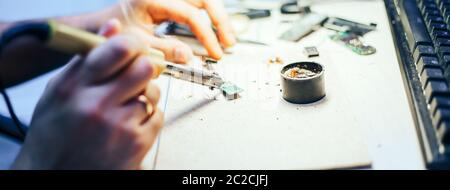 Image of engineer with soldering iron repairing mechanism Stock Photo