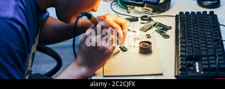 Image of engineer with soldering iron repairing mechanism Stock Photo