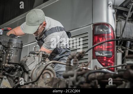 Caucasian Mechanic and the Coach Bus Diesel Engine Regeneration Work. Bus Mechanical Services. Stock Photo