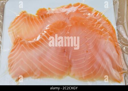 Smoked salmon slices in package on a wooden cutting board close up Stock Photo