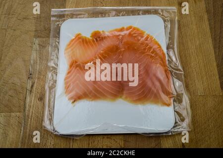 Smoked salmon slices in package on a wooden cutting board close up Stock Photo